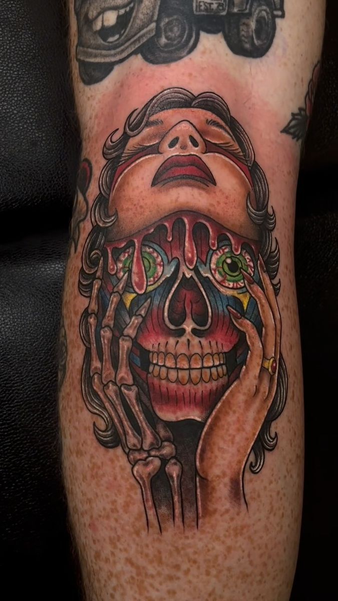 Color tattoo of a woman with a skull face held by hands