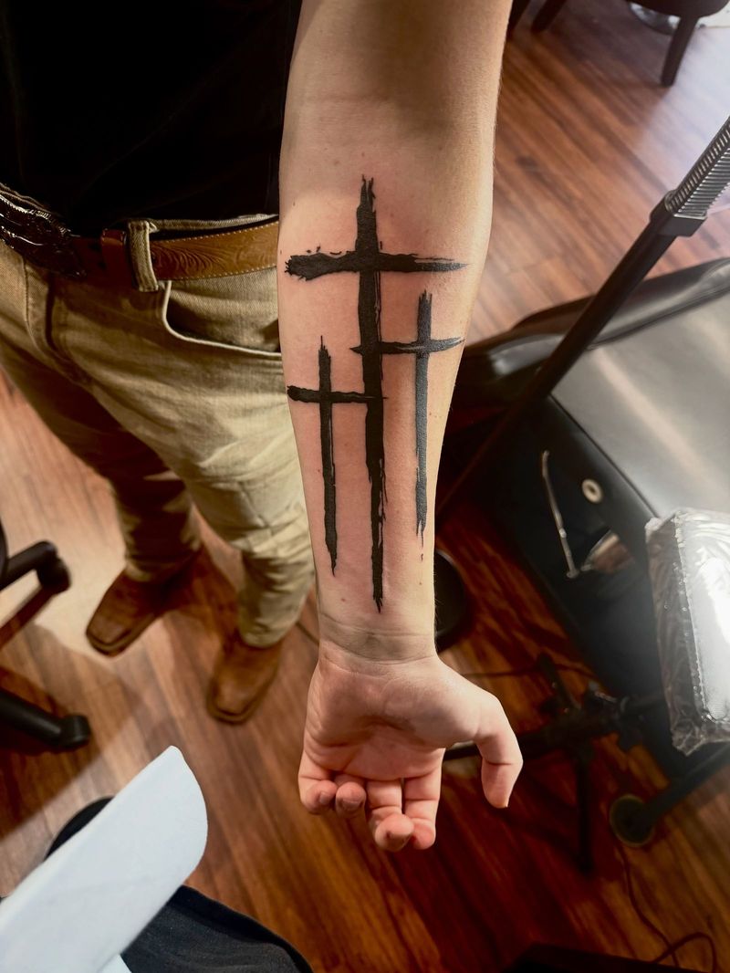 Three brushstroke crosses on a forearm